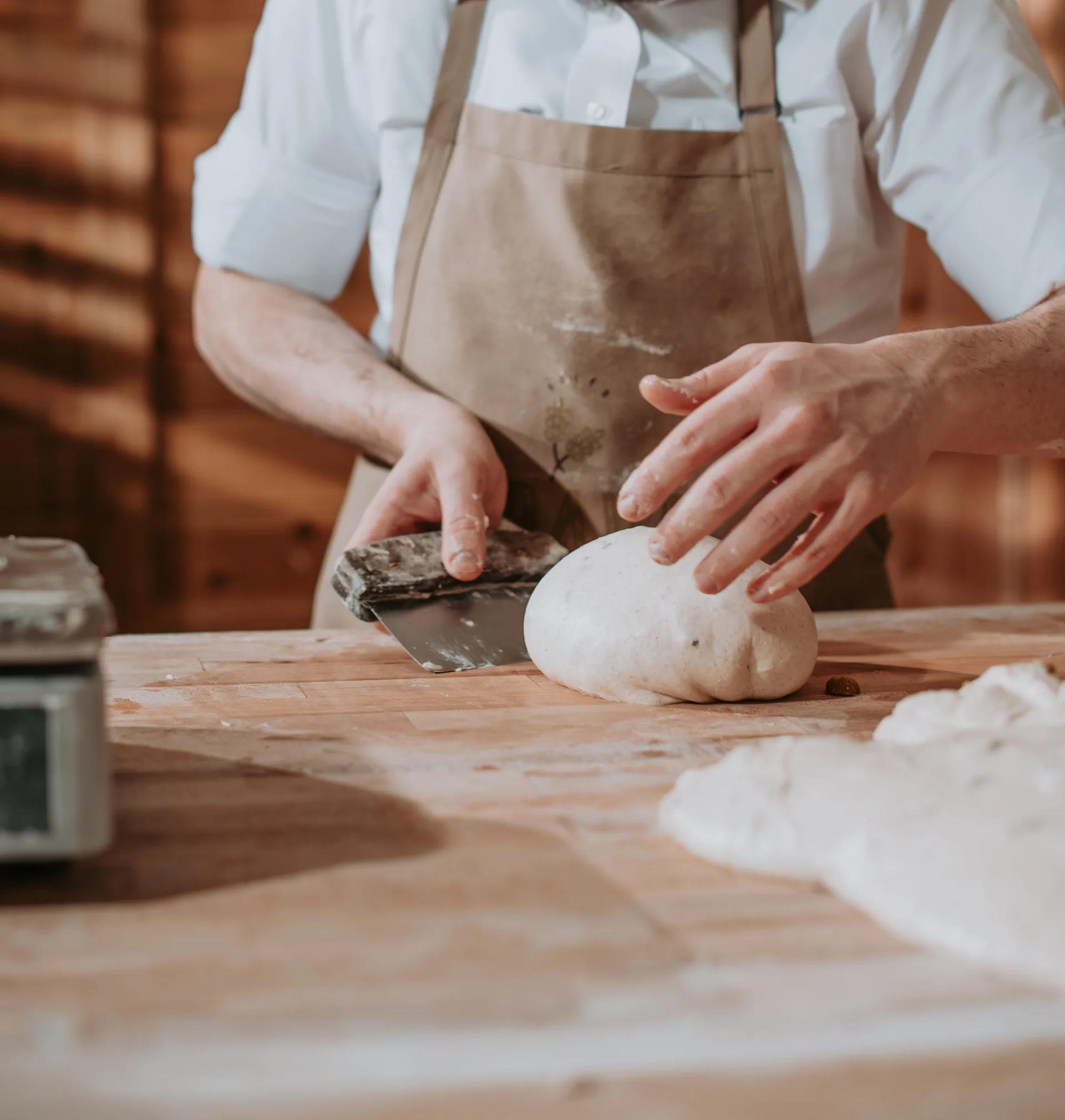 Baker hand shaping Crave Sourdough loaf