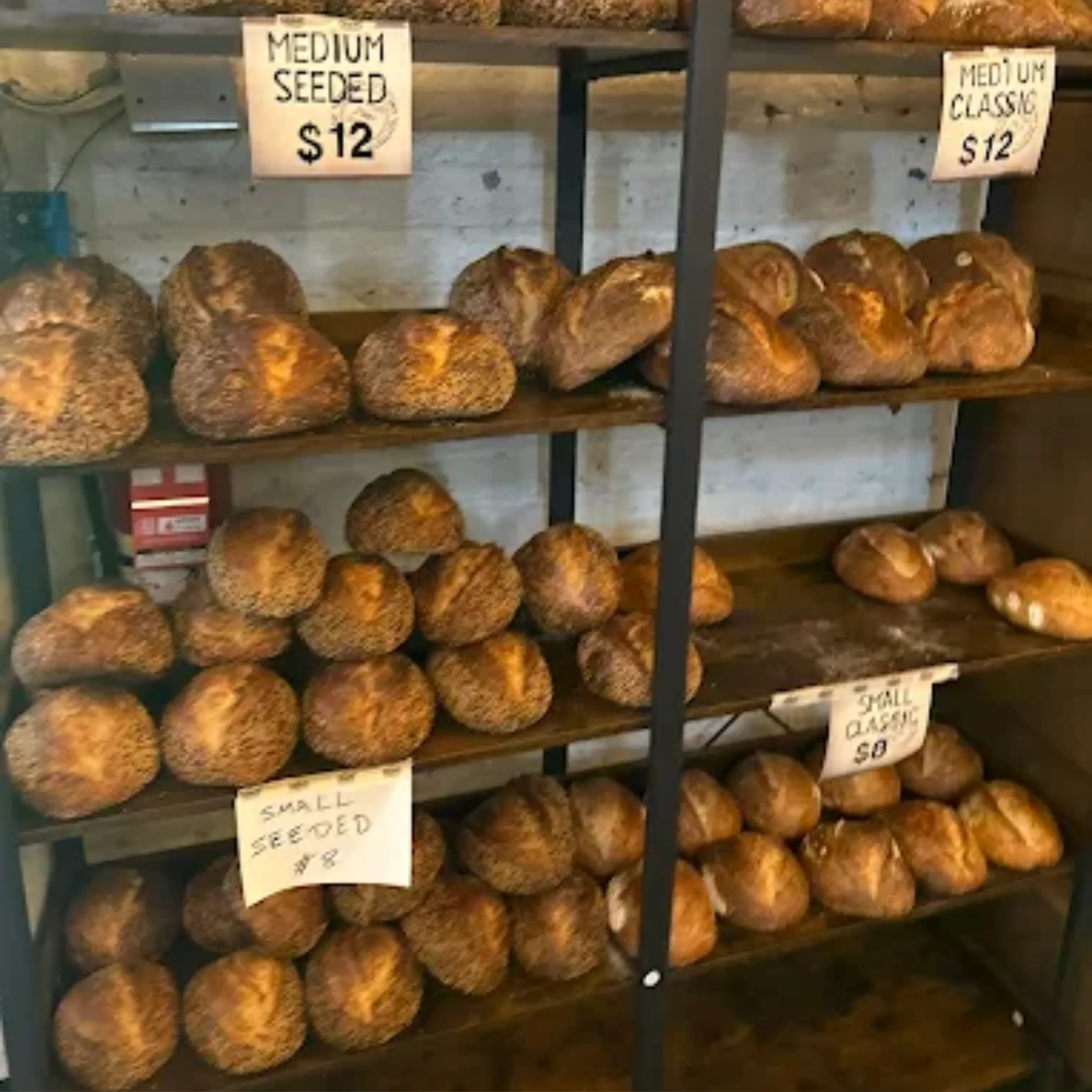 Crave Sourdough loaves on display shelves with hand-written price signs