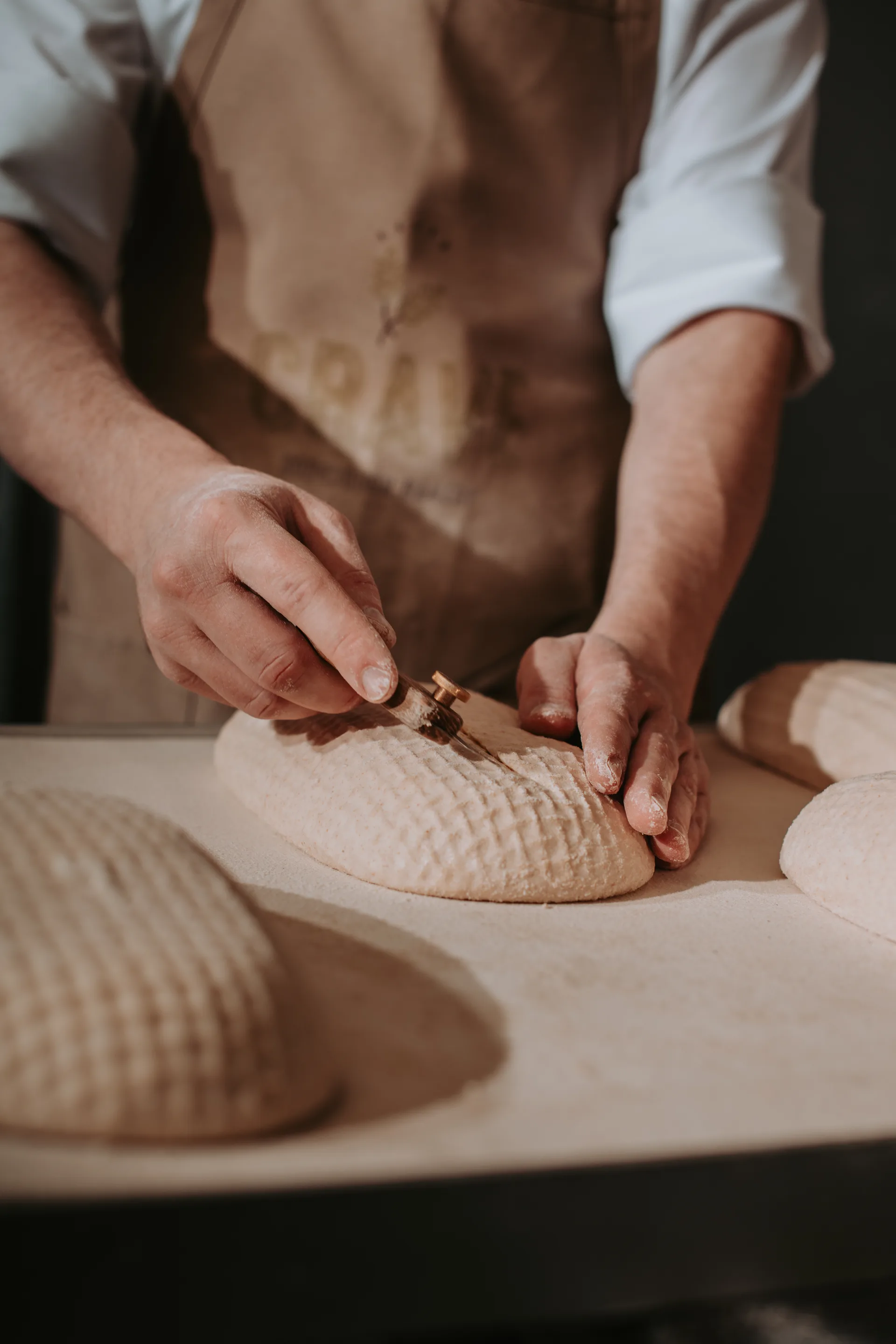 Baker scoring Crave Sourdough loaf with a blade